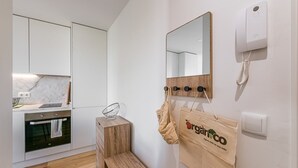 A modern kitchen with white cabinets, a marble countertop, and a wooden stool. - GuestReady - One Step Closer (Porto)