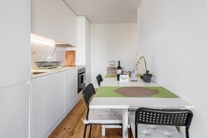 Enjoy a compact kitchen and dining area with oven, white cabinetry, and a dining table for two.