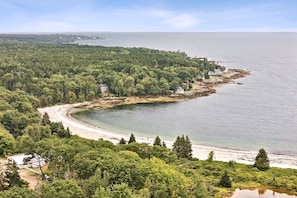Et kystområde med strand, skovklædte arealer og enkelte bygninger.
