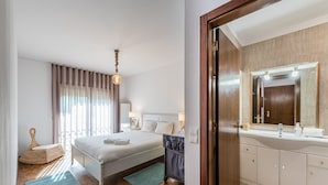 Une chambre d’hôtel comprenant un lit, une table de chevet, une lampe et une salle de bain avec un lavabo et un miroir.