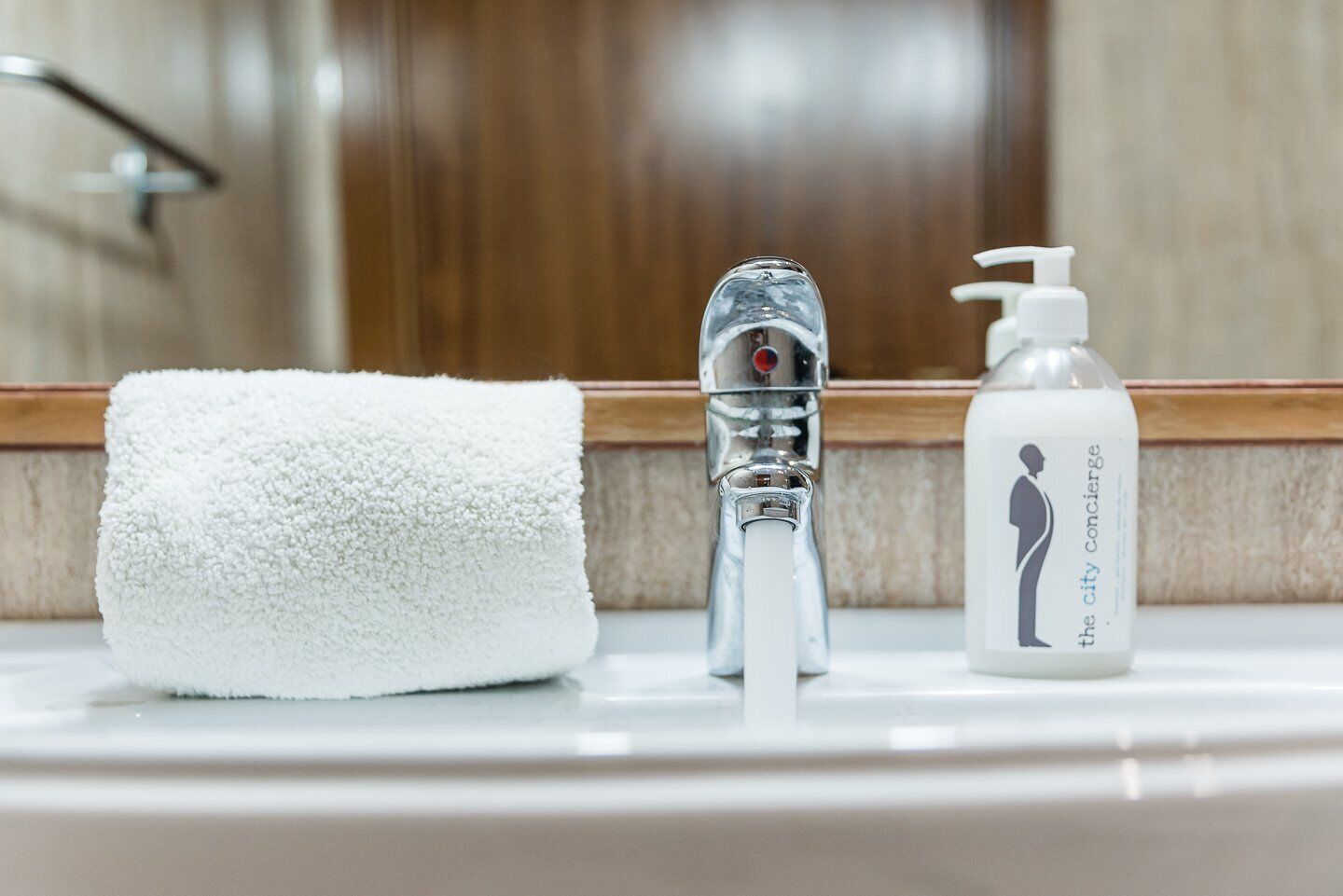 A bathroom sink with a white towel, a chrome faucet, and a bottle of soap.