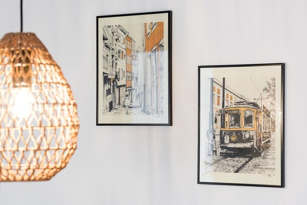Trois œuvres d’art encadrées accrochées au mur, un luminaire suspendu et un tramway.