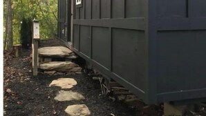 A cabin with a stone pathway leading to the entrance, surrounded by trees.