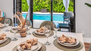 A dining table set for four with white plates, clear wine glasses, and a decorative vase. - Chic + Upscale + Heated Pool | 15 min FLL & Beach (Plantation)