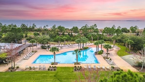 Ein Resort mit großem Pool, Liegestühlen und Blick auf den Ozean bei Sonnenuntergang.