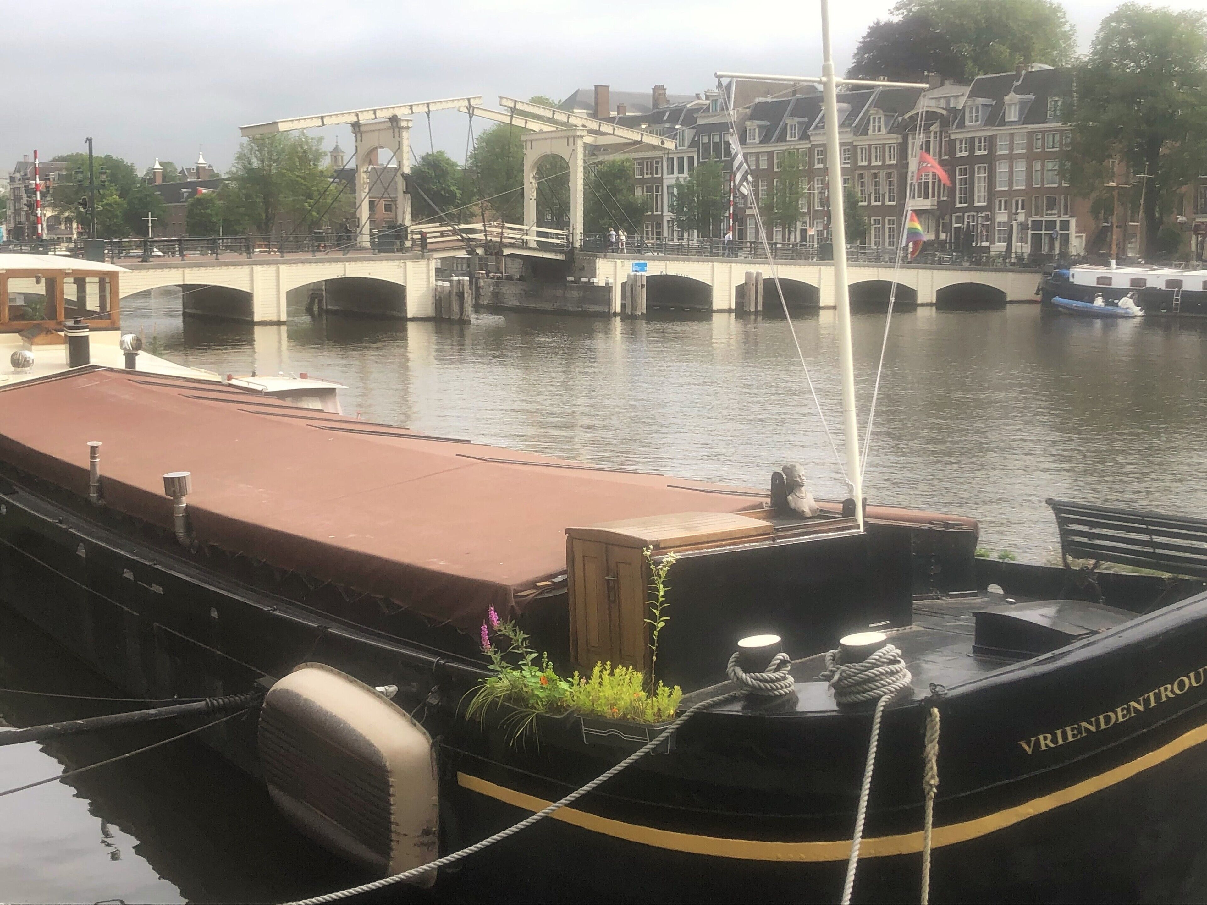 A boat docked at a canal with a bridge in the background.
