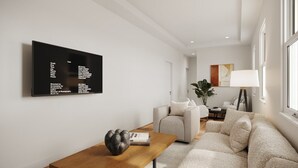 A modern living room with a flat-screen TV mounted on the wall, a wooden coffee table with a decorative object, a beige sofa, and a white armchair. - Compound for Families- Main House with Adjacent Cottages Cabins,Indoor Pool Spa (Fennville)
