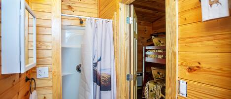 A wooden cabin bathroom with a sink, mirror, and shower curtain.