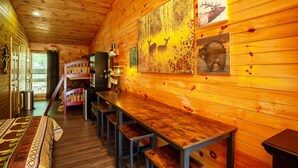 Un interior de madera con una larga mesa de comedor, bancos y arte mural con ciervos y alces.