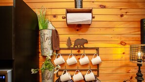 Una cocina con paredes de madera, un refrigerador, un colgador para tazas y un adorno con forma de oso.