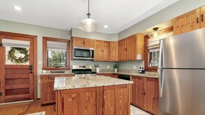 A modern kitchen with wooden cabinets, stainless steel appliances, and a central island.