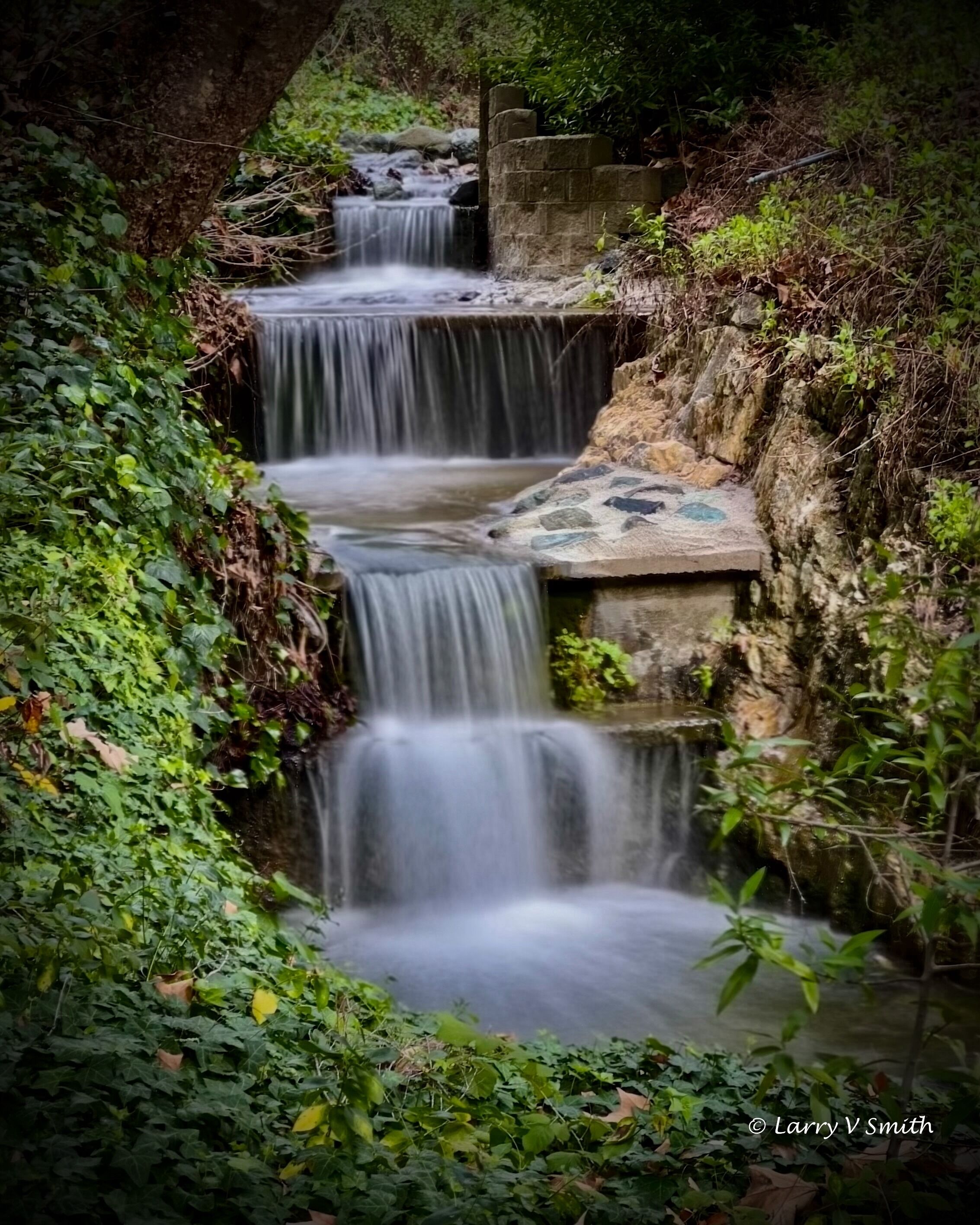 Ein mehrstufiger Wasserfall in üppiger, grüner Landschaft.
