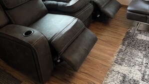 Ein modernes Wohnzimmer mit einer Ledersofa, einem kleinen Tisch und einem Bärenbild an der Wand.
