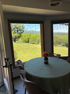 Een eethoek met een ronde tafel, stoelen en een vaas met bloemen.