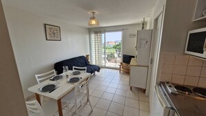 A compact kitchen with a dining area, a bed, and a view of the outside. - Royan - APARTMENT with SEA VIEW - ONLY 300m from the BEACH and SHOPS (ROYAN)