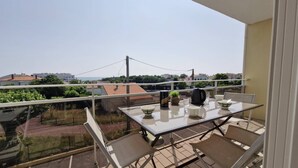 A balcony with a table set for two, chairs, a kettle, and a bowl. - Royan - APARTMENT with SEA VIEW - ONLY 300m from the BEACH and SHOPS (ROYAN)