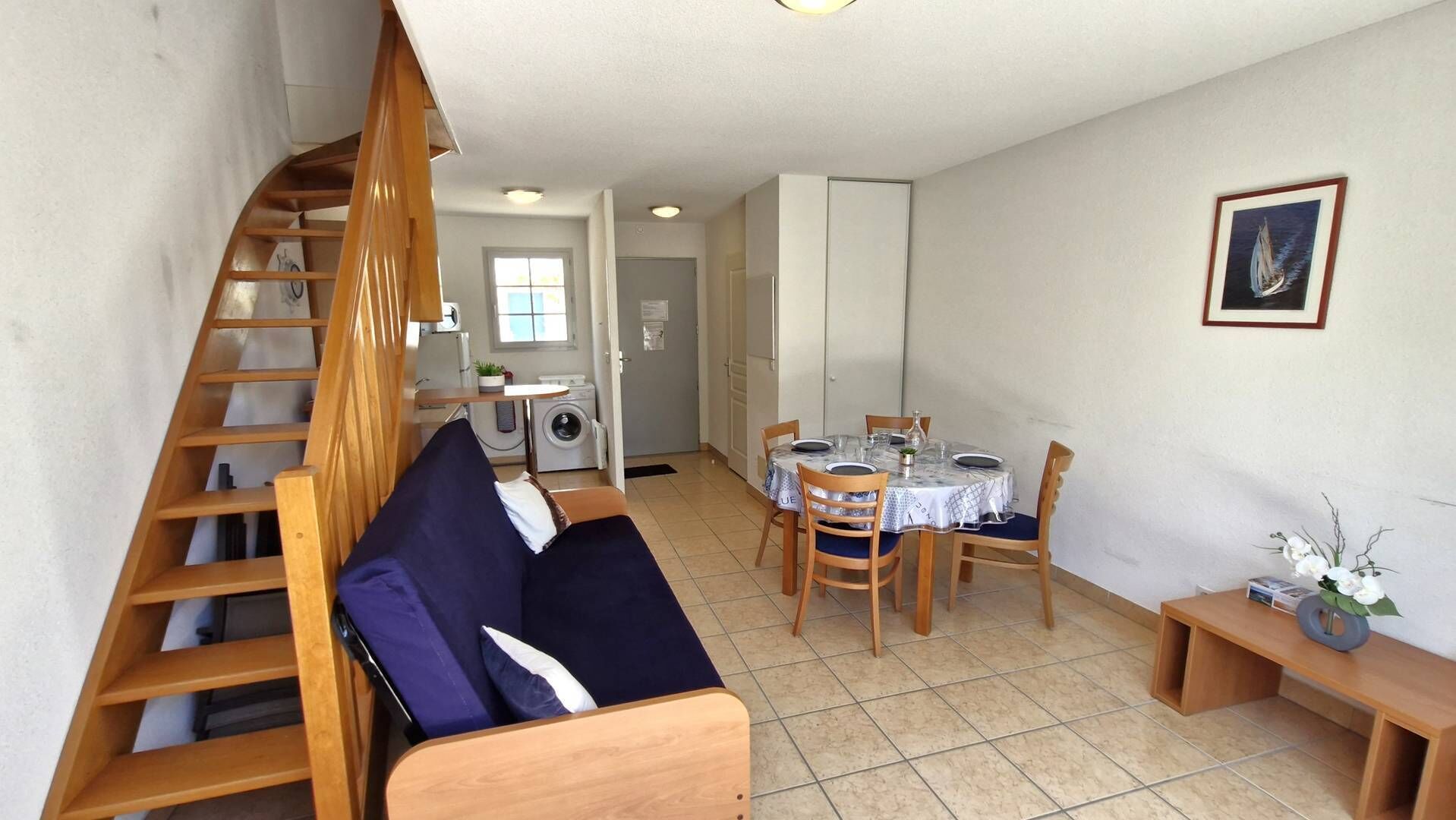 Un espacio habitable compacto con un entrepiso para el dormitorio, una zona de comedor y una cocina.