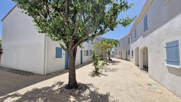 Ein Innenhof mit weißen Gebäuden, blauen Fensterläden und einem Baum.