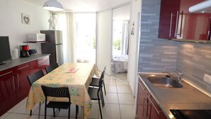A compact kitchen with a dining table, chairs, a microwave, and a refrigerator.