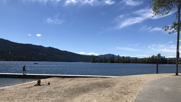 A lakeside view with a sandy beach, a pier, and mountains in the background. - Cozy Studio (Sandpoint)