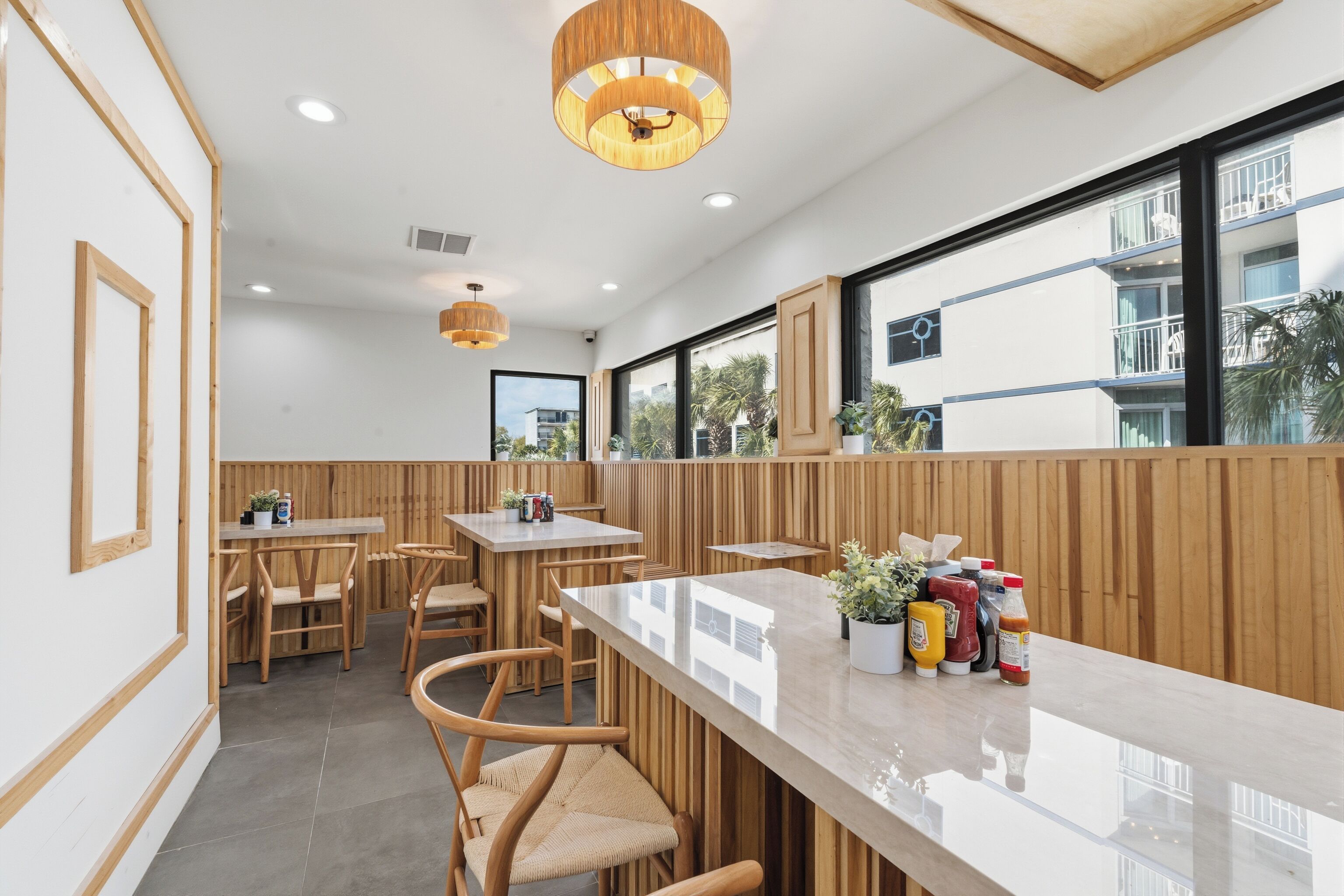 Een modern restaurant met houten lambrisering, een bar en grote ramen met uitzicht op buiten.