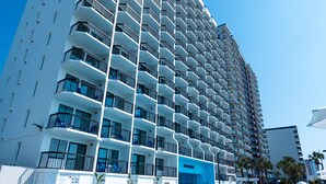 A high-rise hotel with a swimming pool, multiple balconies, and a clear blue sky. - Grande Beach Resort (Myrtle Beach)