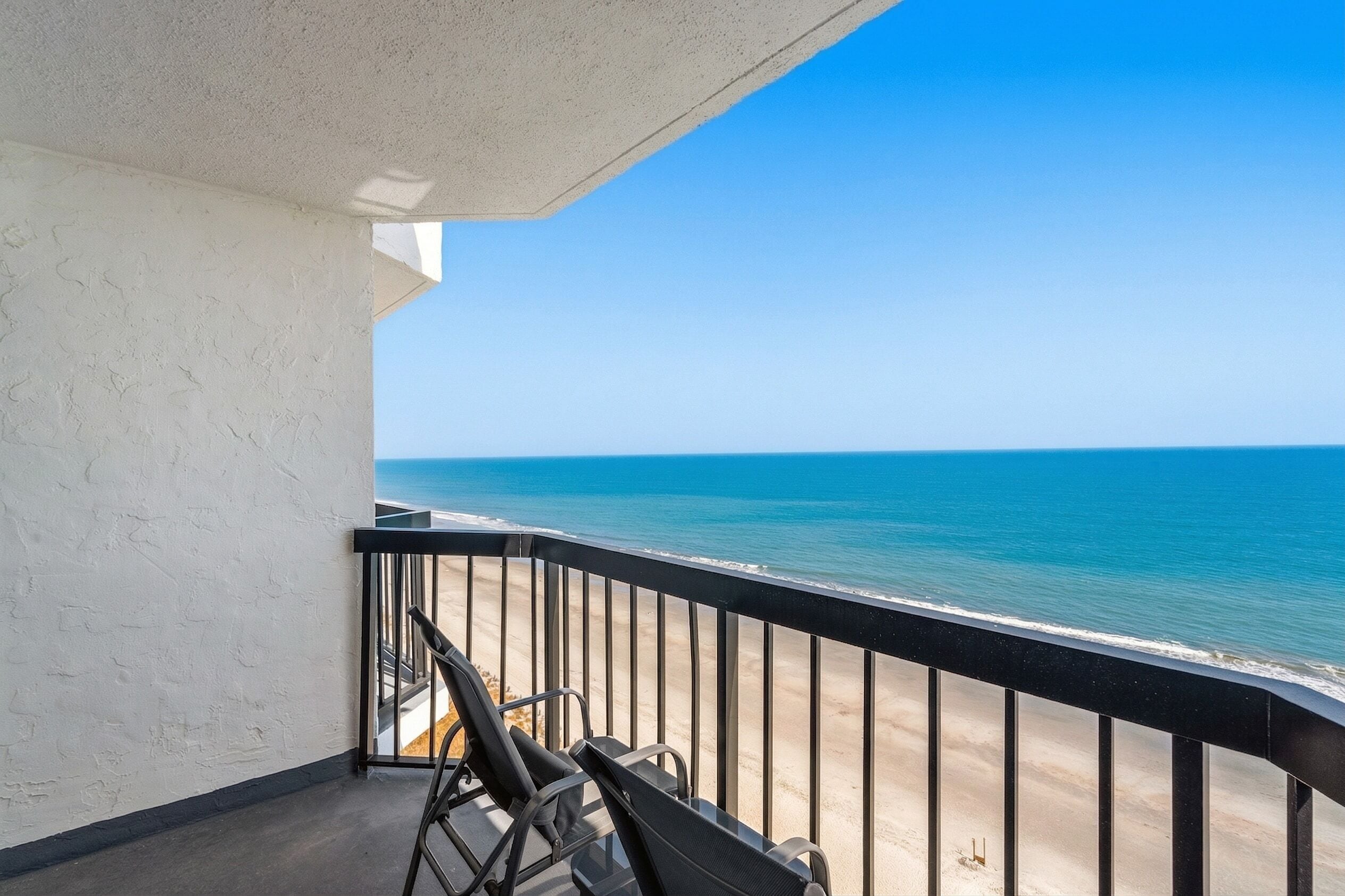 A balcony with a view of the ocean, a chair, and a bicycle.