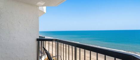 A balcony with a view of the ocean, a chair, and a bicycle.
