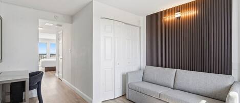 En moderne stue med sofa, spiseområde med bord og stole, samt et garderobeskab.