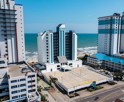 Un hotel con estacionamiento, vista al mar y un cartel que dice "GRAND BEACH".