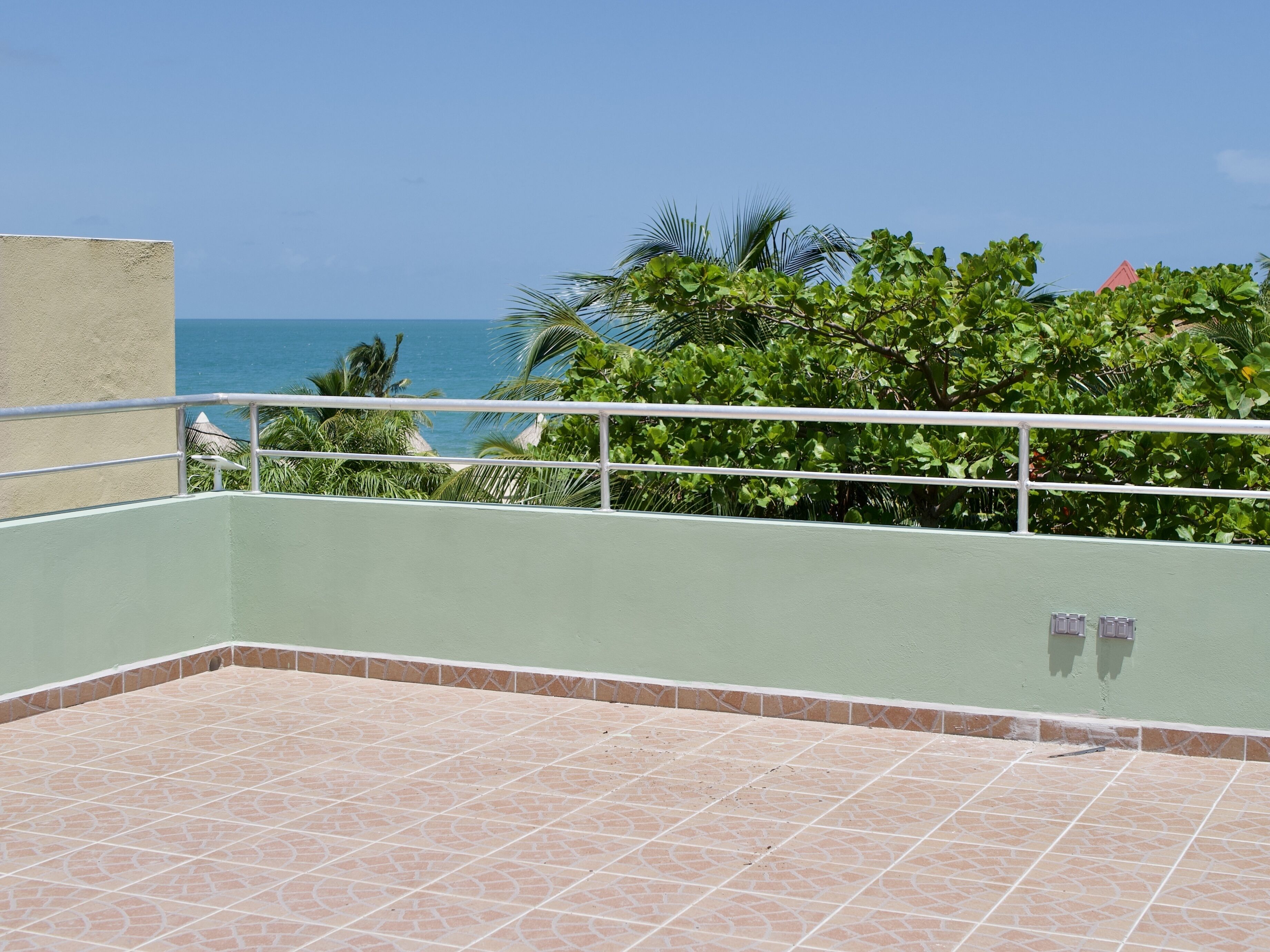 Un balcone con vista sull'oceano, circondato da una vegetazione lussureggiante.