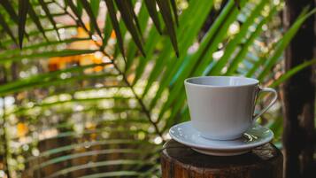A white cup and saucer on a wooden stump with green foliage in the background.