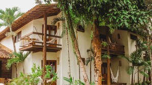 A two-story building with balconies, surrounded by lush greenery and palm trees. - Pousada Villa Bella (Itacaré)