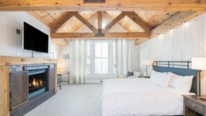 A bedroom with a fireplace, a bed, a nightstand, and a TV mounted on the wall. - Luxury Home | Hot Tub, Decks + Sweeping Mountain views (Mountain Village)