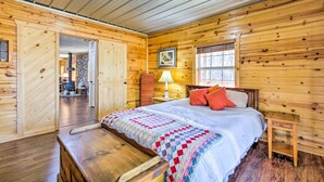 A wooden cabin bedroom with a bed, a nightstand, a lamp, and a bench. - Pet-Friendly Ellijay Escape w/ Yard & Grill! (Ellijay)