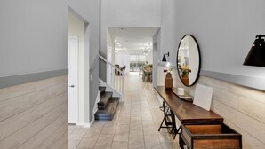 A modern interior with a staircase leading to a dining area, a wooden bench with storage, and a large mirror on the wall. - Refined stay Disney Theme 8BR Resort Villa With FREE Heated Pool/Spa Near Disney (Davenport)