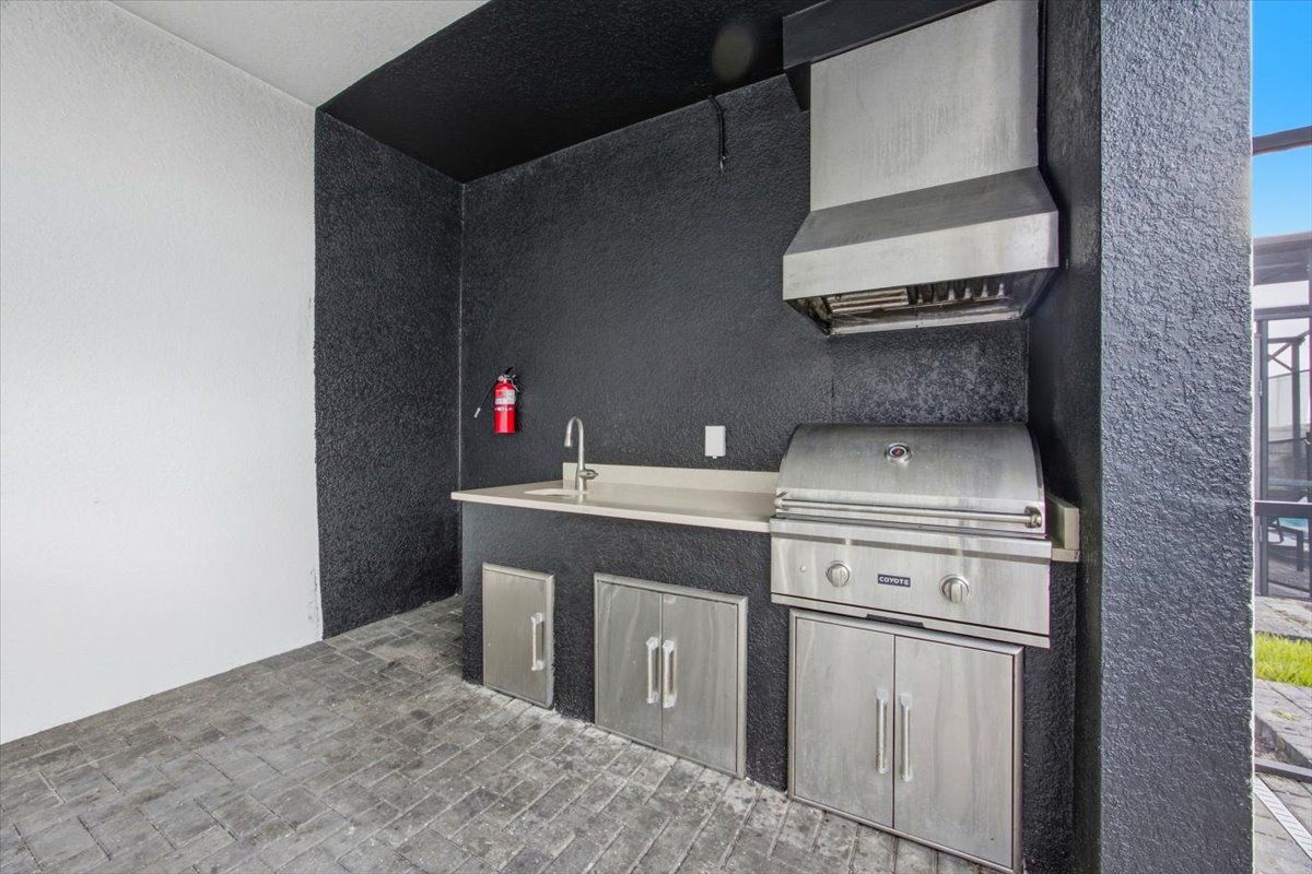 A compact outdoor kitchen with a built-in grill, a sink, and storage cabinets.
