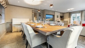 A modern dining area with a large wooden table set for six, surrounded by upholstered chairs. - House Hansen Hus, Germany (Sylt)