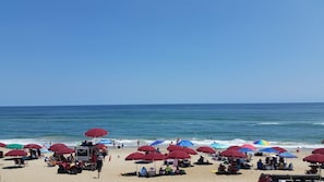 A beach with multiple umbrellas and beach chairs, a lifeguard stand, and the ocean in the background. - BIS-Duck - Spacious 2BR/2.5BA - Great Pools and Beach! (Duck)