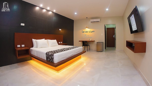 A modern hotel room with a large bed, bedside tables, a desk with a chair, a small fridge, and a TV mounted on the wall. - HOTEL OSHO (Santa Cruz)