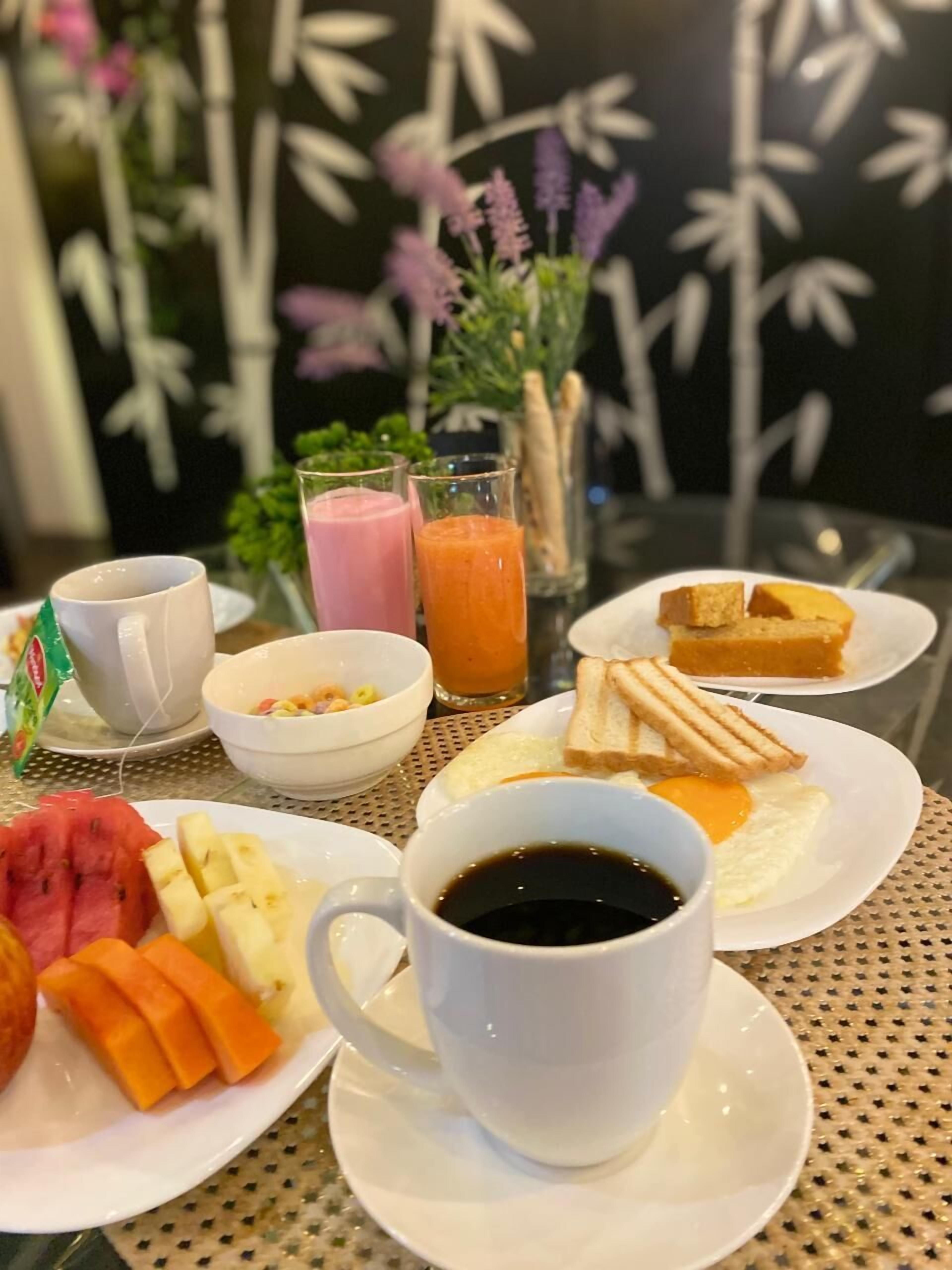 Une table mise pour le petit-déjeuner avec une tasse de café, des assiettes de toasts, des fruits et du jus.