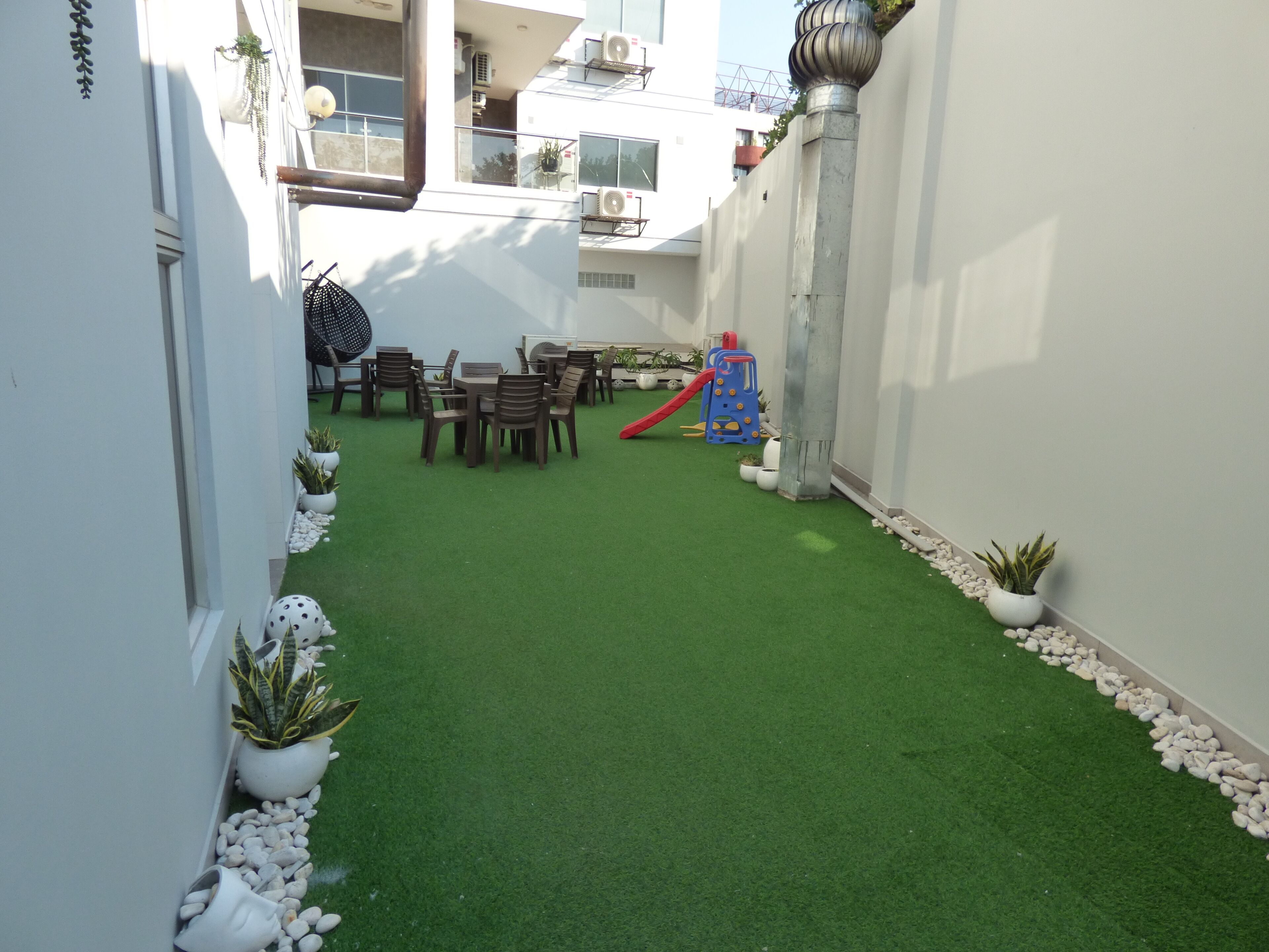 Un patio con césped artificial, una zona de juegos y un comedor.