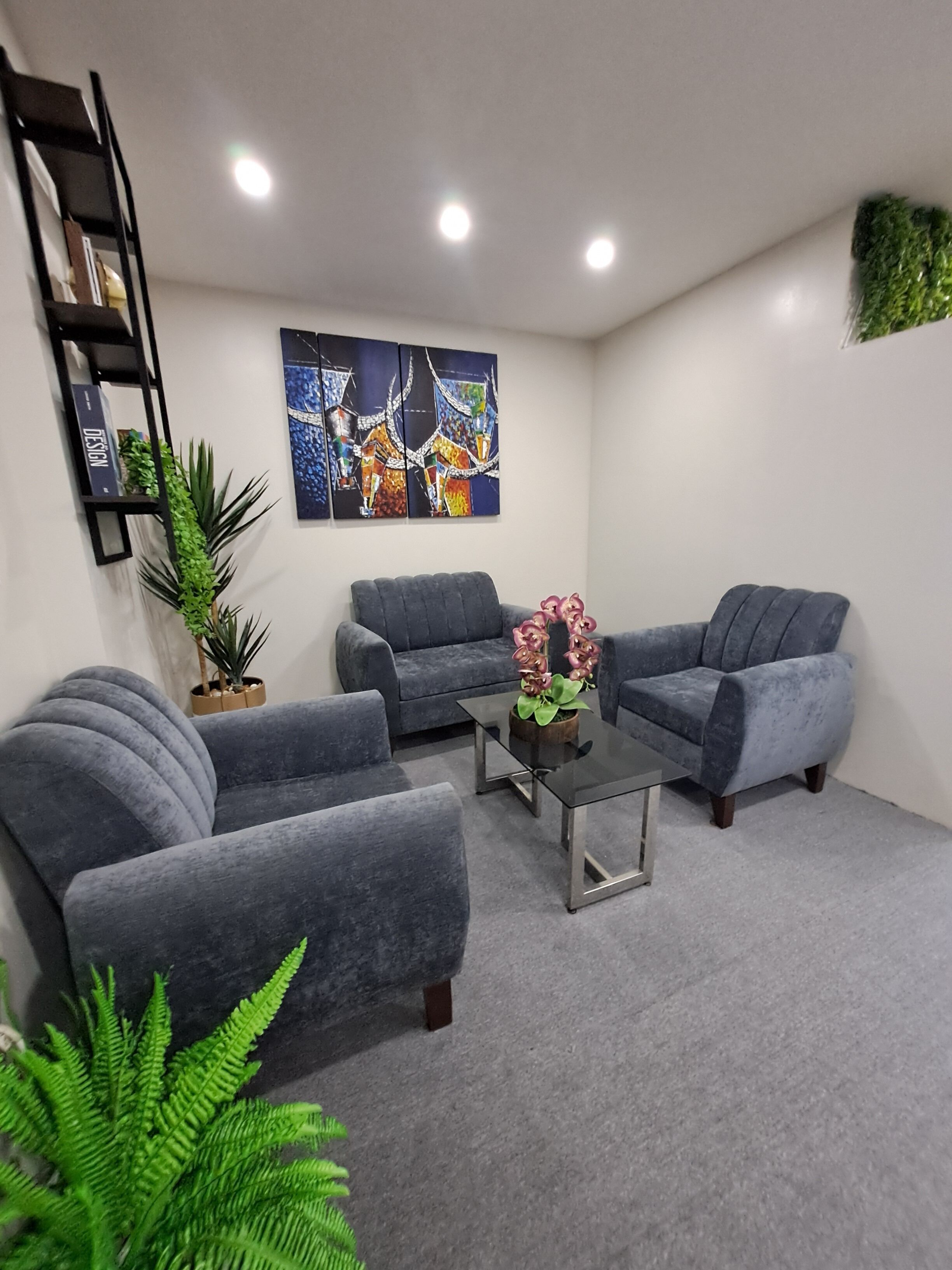 A modern living room with grey sofas, a coffee table, and a bookshelf.