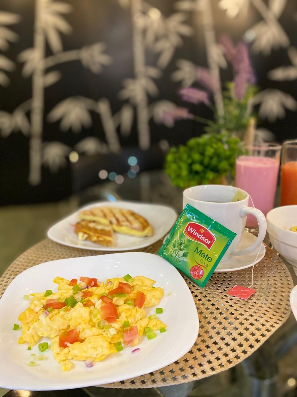Un desayuno con huevos revueltos, tostadas, una taza de café y un batido.