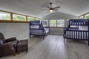 A room with bunk beds, a leather chair, and large windows. - River Rat's Rest (Homosassa)