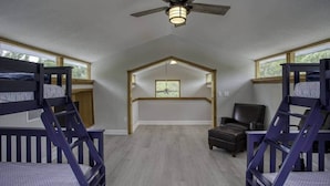 A room with bunk beds, a ceiling fan, a window, and a chair. - River Rat's Rest (Homosassa)