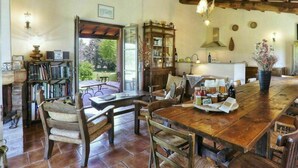 Uma área de jantar rústica com mesa e cadeiras de madeira, uma estante e vista para o exterior.