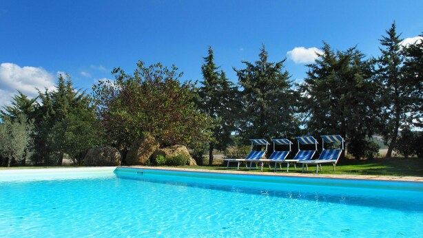 A clear swimming pool with lounge chairs and a rocky landscape. - Lovely apartment in villa for 5 guests with pool, WIFI, TV, terrace and panoramic view (Pomarance)