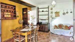 A rustic dining area with wooden furniture, a tiled floor, and a shelf with kitchen utensils. - Lovely apartment in villa for 5 guests with pool, WIFI, TV, terrace and panoramic view (Pomarance)
