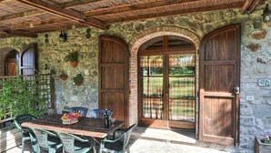 Ein rustikales Steinhaus mit Holztüren und einer überdachten Terrasse.